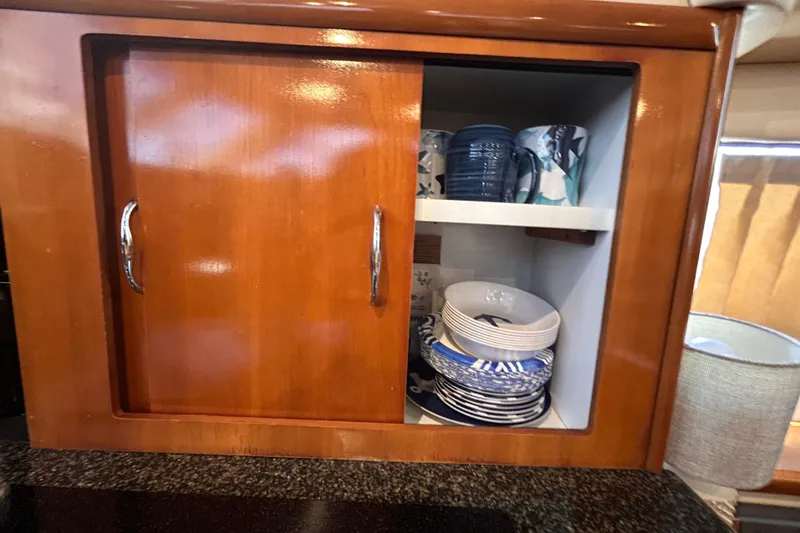 Slide: The Image of Wooden cabinet with dishes and mugs inside a 2005 Carver 36 Motor Yacht kitchen. - 85