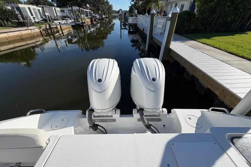 Slide: The Image of 2025 Sea Hunt Gamefish 27CB with dual outboard motors docked by a canal. - 71