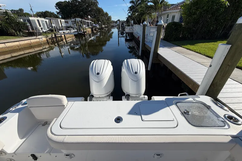 Slide: The Image of 2025 Sea Hunt Gamefish 27CB boat docked in a serene canal setting. - 64
