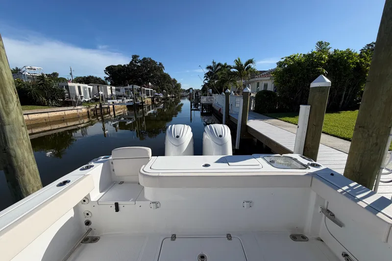 Slide: The Image of 2025 Sea Hunt Gamefish 27CB boat docked in a serene canal setting. - 59
