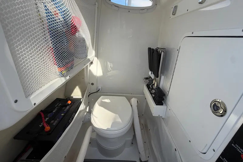 Slide: The Image of Interior of 2025 Sea Hunt Gamefish 27CB boat, featuring compact marine toilet setup. - 40