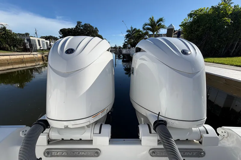 Slide: The Image of 2025 Sea Hunt Gamefish 27CB boat with dual outboard engines docked by a canal. - 73
