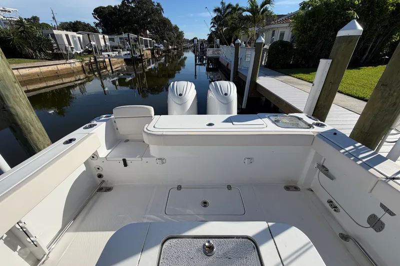 Slide: The Image of 2025 Sea Hunt Gamefish 27CB boat interior, featuring spacious deck and dual engines, docked by a canal. - 58