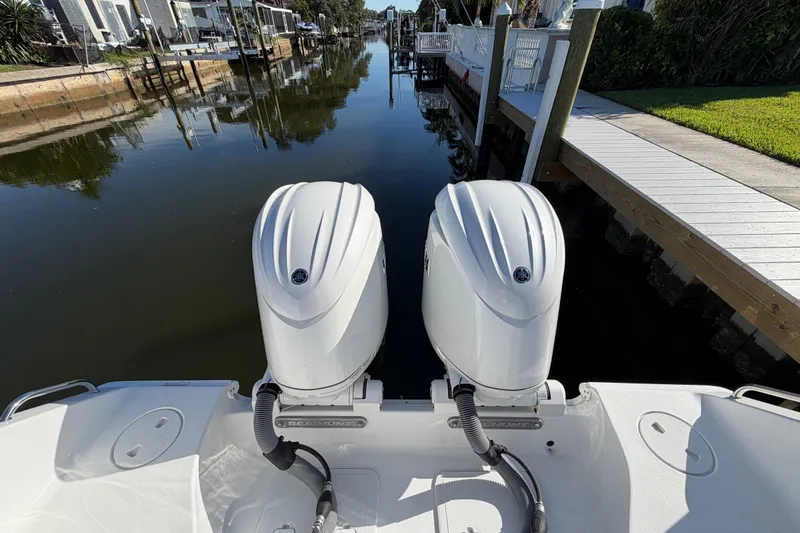 Slide: The Image of 2025 Sea Hunt Gamefish 27CB boat with dual outboard engines docked by a canal. - 72