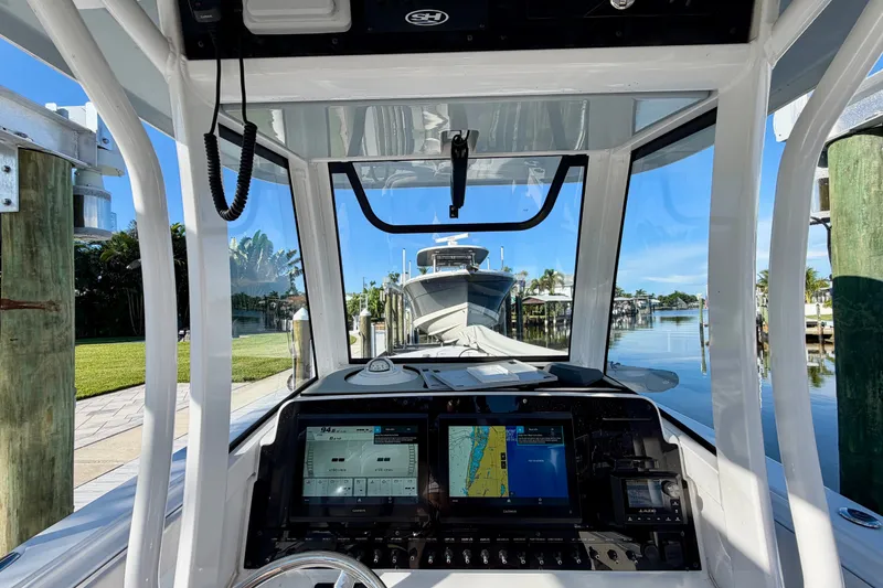 Slide: The Image of Interior view of 2025 Sea Hunt Gamefish 27CB boat with navigation screens and marina backdrop. - 26