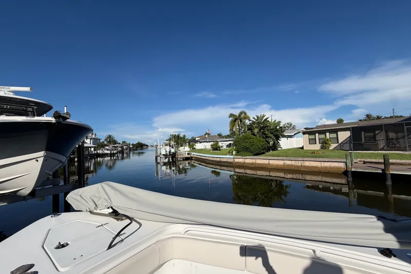 Slide: The Image of 2025 Sea Hunt Gamefish 27CB boat docked in a serene canal setting. - 46