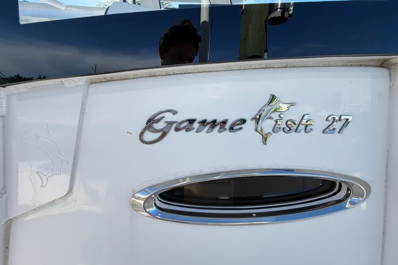 Slide: The Image of Das Bild zeigt das Logo des Sea Hunt Gamefish 27CB von 2025 auf einem weißen Boot. - 77