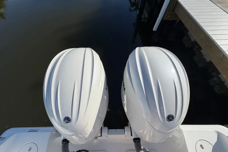 Slide: The Image of Twin outboard engines on a 2025 Sea Hunt Gamefish 27CB boat docked by the water. - 74