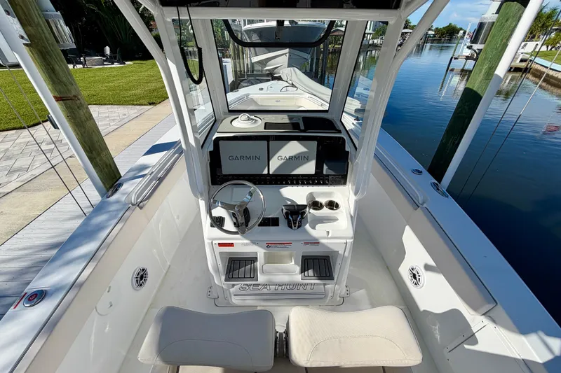 Slide: The Image of 2025 Sea Hunt Gamefish 27CB boat cockpit with Garmin navigation system, docked by the water. - 24