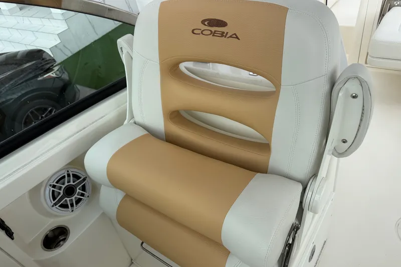 Slide: The Image of Cobia 240 Dual Console 2021 boat seat with tan and white upholstery. - 31