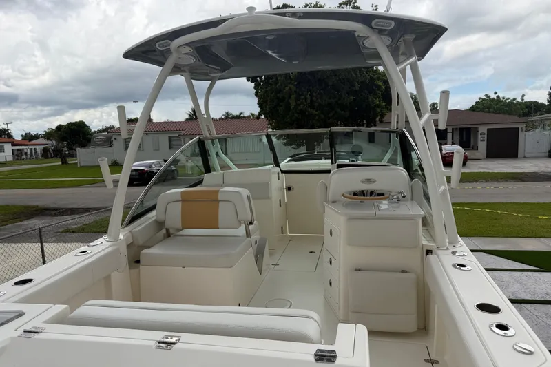 Slide: The Image of 2021 Cobia 240 Dual Console boat with seating and helm, parked in a residential area. - 28