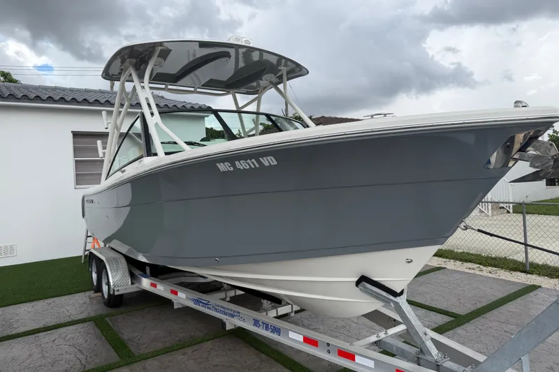 Slide: The Image of 2021 Cobia 240 Dual Console boat on trailer, parked beside a house under cloudy skies. - 16