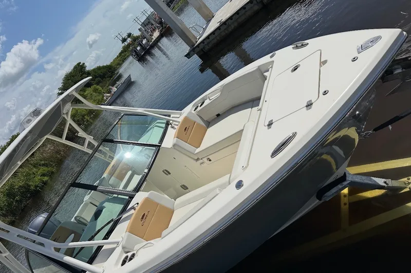 The Image of 2021 Cobia 240 Dual Console boat docked by a scenic waterfront. - 6