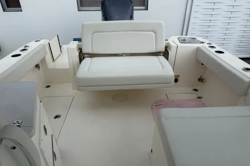 Slide: The Image of 2021 Cobia 240 Dual Console boat interior with white seating and storage compartments. - 32