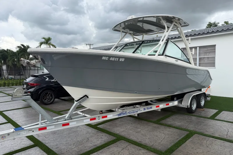 Slide: The Image of 2021 Cobia 240 Dual Console boat on trailer, parked outdoors under cloudy skies. - 17