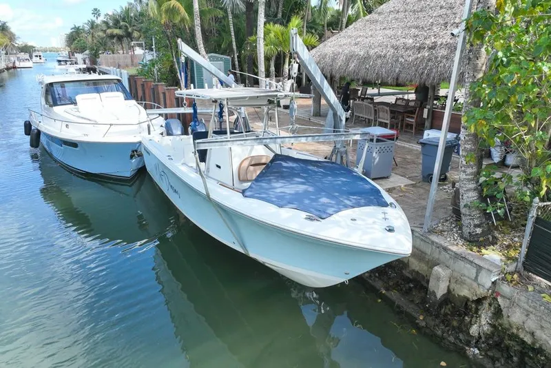 Slide: The Image of 2005 Sailfish 2660 CC boat docked beside another vessel in a tropical setting. - 0