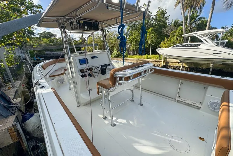 Slide: The Image of 2005 Sailfish 2660 CC boat interior with helm, seating, and canopy in a sunny setting. - 22
