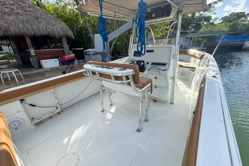 Slide: The Image of 2005 Sailfish 2660 CC boat with spacious deck and seating, docked near a thatched hut. - 20