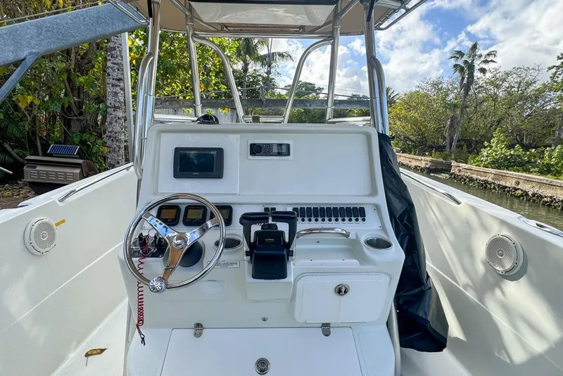 Slide: The Image of 2005 Sailfish 2660 CC boat cockpit with steering wheel and control panel, surrounded by lush greenery. - 24