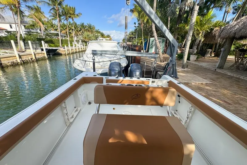 Slide: The Image of 2005 Sailfish 2660 CC boat docked by palm trees and waterfront homes. - 31
