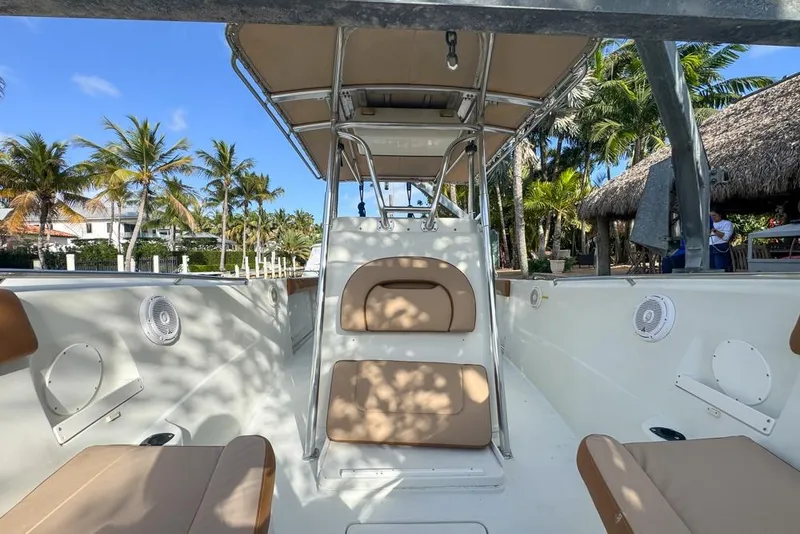 Slide: The Image of 2005 Sailfish 2660 CC boat interior with seating, palm trees, and blue sky background. - 12
