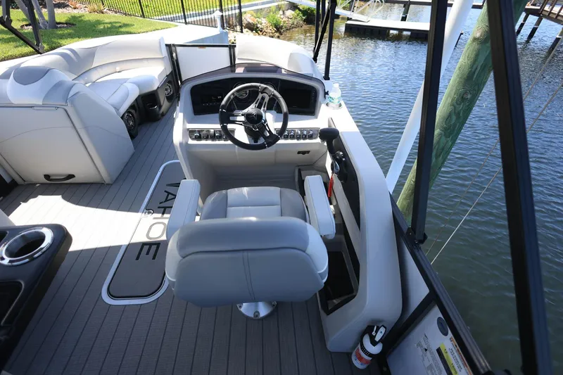 Slide: The Image of 2025 Tahoe Pontoon LTZ 23 interior with steering wheel and seating, docked by water. - 17