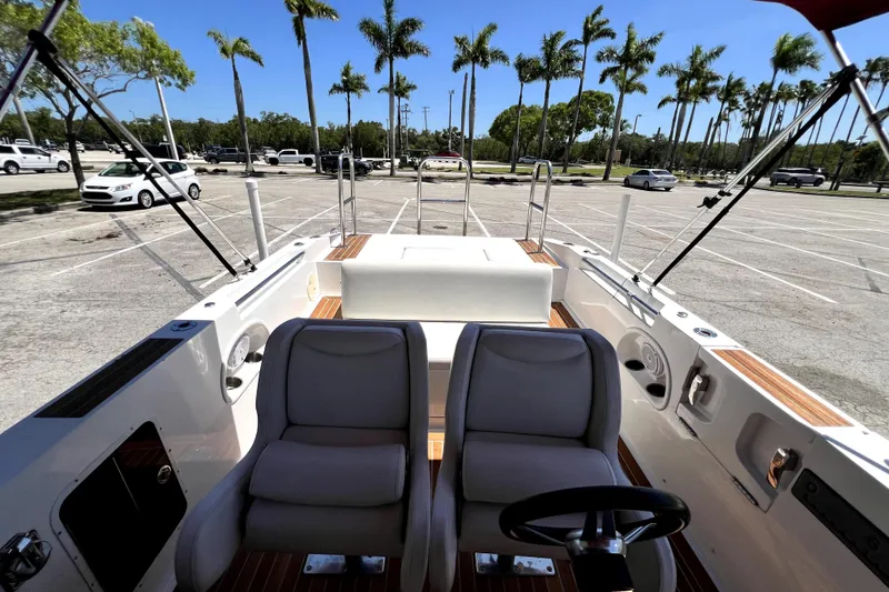 Slide: The Image of 2013 Novurania Chase 23 boat interior with seating, parked in a sunny lot with palm trees. - 48