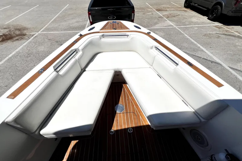 Slide: The Image of 2013 Novurania Chase 23 boat interior with white seating and wooden deck in a parking lot. - 45