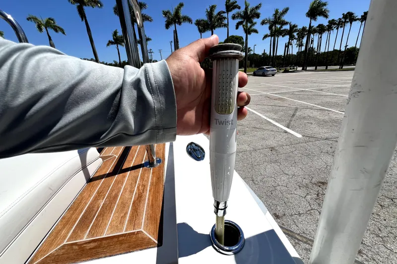Slide: The Image of Hand holding a twist handle on a 2013 Novurania Chase 23 boat, with palm trees in background. - 77