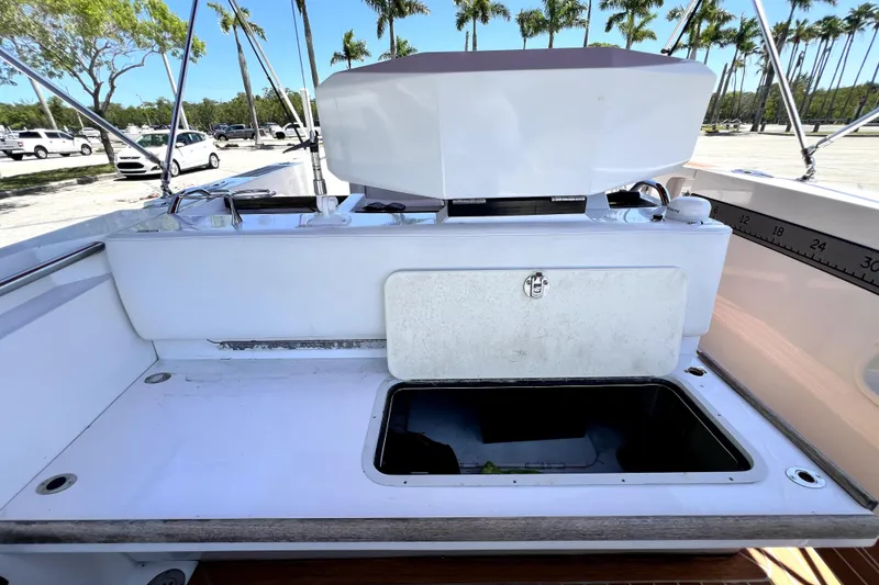 Slide: The Image of 2013 Novurania Chase 23 boat interior with open storage compartment and palm trees in background. - 58