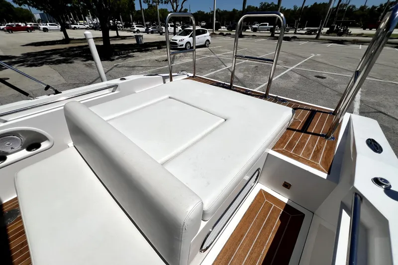 Slide: The Image of 2013 Novurania Chase 23 boat with white seating and wooden deck in a parking area. - 30