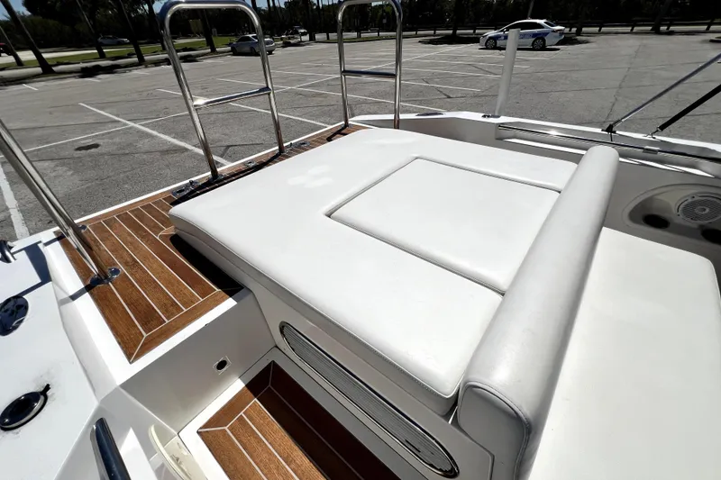 Slide: The Image of 2013 Novurania Chase 23 boat with white seating and wooden deck in a parking lot. - 72
