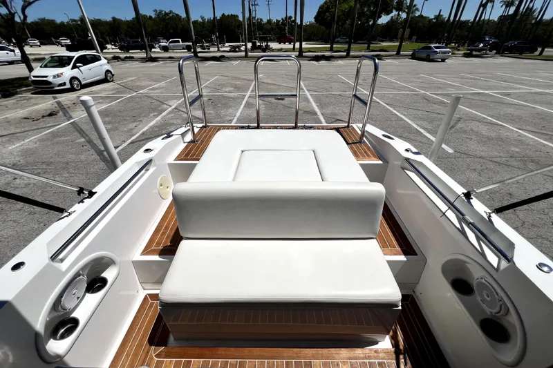 Slide: The Image of 2013 Novurania Chase 23 boat interior with white seating and wood accents in a parking lot. - 68