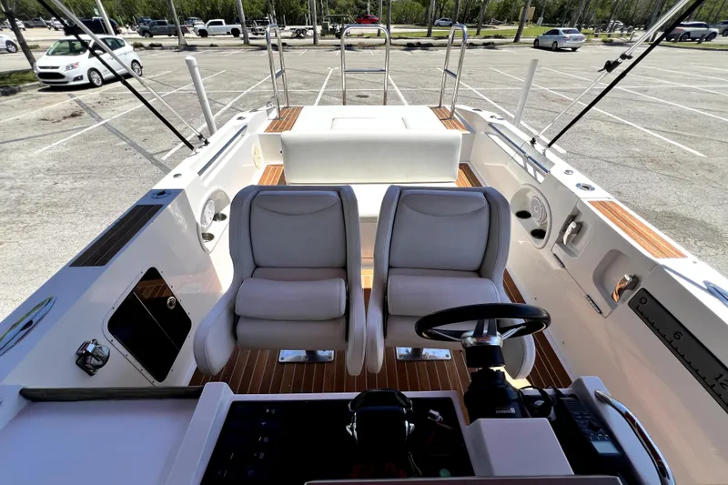 Slide: The Image of 2013 Novurania Chase 23 boat interior with dual seats and steering wheel in a parking lot. - 44