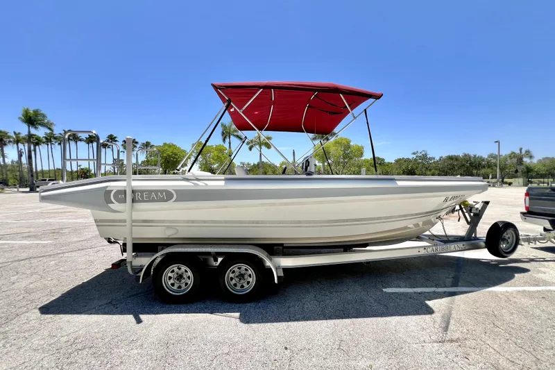 Slide: The Image of 2013 Novurania Chase 23 boat on trailer with red canopy in sunny parking lot. - 1