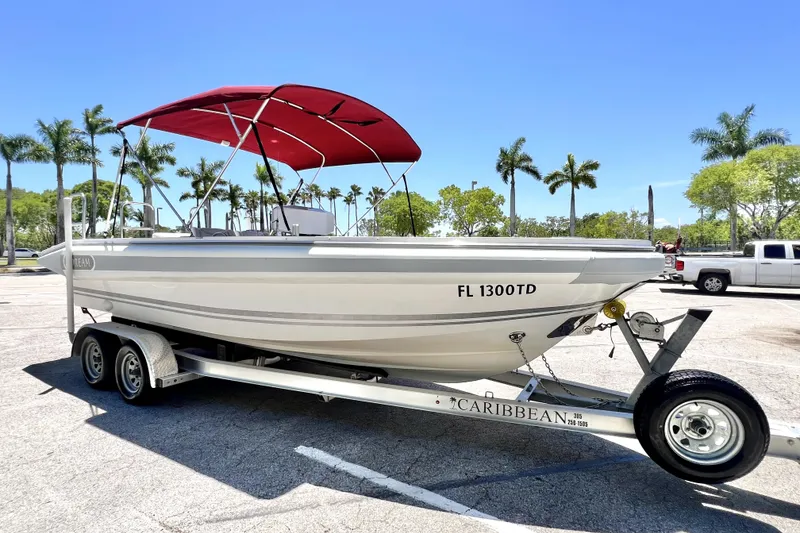 Slide: The Image of 2013 Novurania Chase 23 boat on trailer with red canopy, parked under clear blue sky. - 0