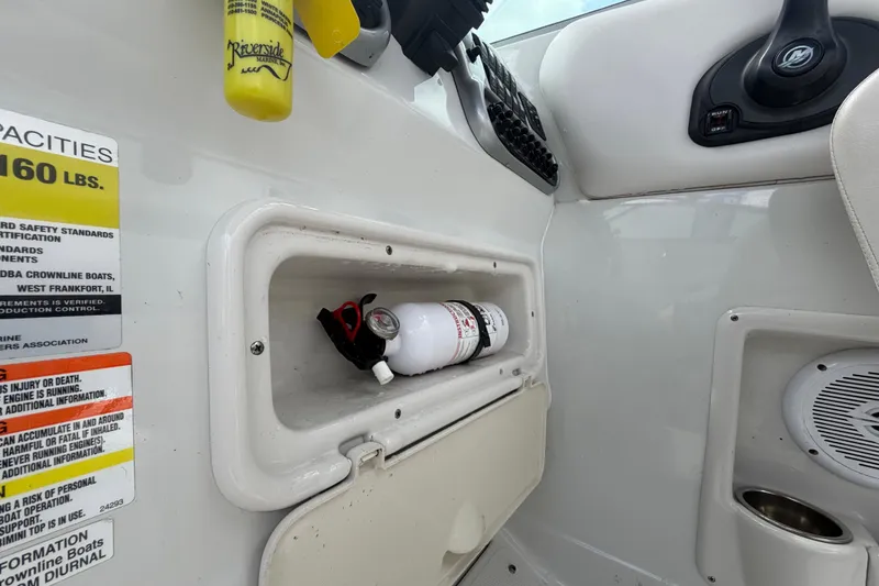 Slide: The Image of Interior of a 2012 Crownline 236 SC boat showing storage compartment and safety labels. - 44
