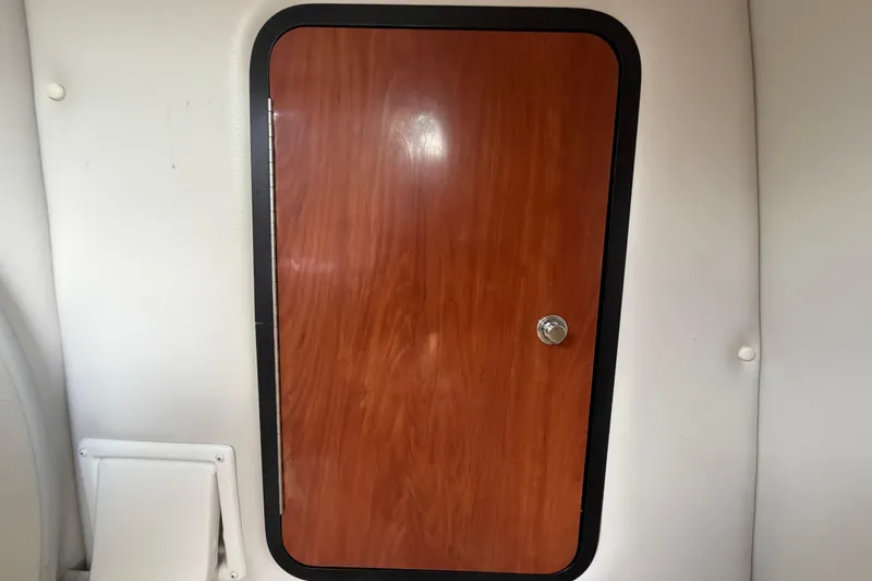 Slide: The Image of Wooden cabin door inside 2012 Crownline 236 SC boat, featuring sleek design and chrome handle. - 68