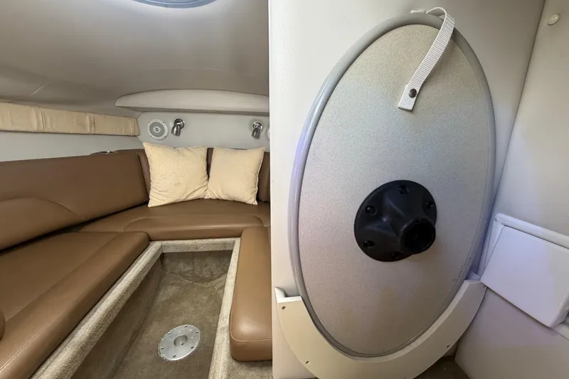 Slide: The Image of 2012 Crownline 236 SC cabin interior with brown seating and storage compartment. - 70