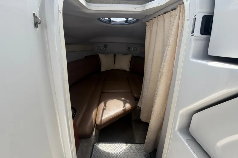 Slide: The Image of 2012 Crownline 236 SC cabin interior with brown seating and beige curtain. - 52