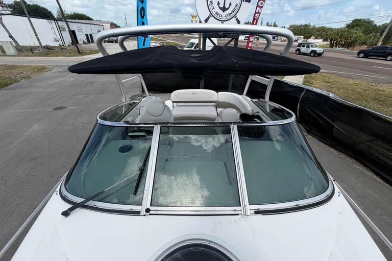 Slide: The Image of 2012 Crownline 236 SC boat with black canopy, parked on a paved road. - 77