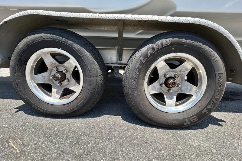 Slide: The Image of Trailer wheels of a 2012 Crownline 236 SC boat on pavement. - 97