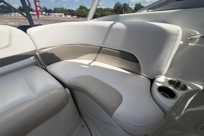 Slide: The Image of 2012 Crownline 236 SC boat interior seating with cup holders, featuring sleek white and beige upholstery. - 84