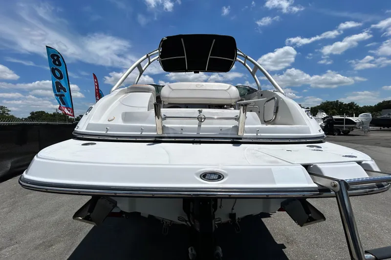 Slide: The Image of 2012 Crownline 236 SC boat, rear view, sunny day, blue sky, dealership flags. - 3
