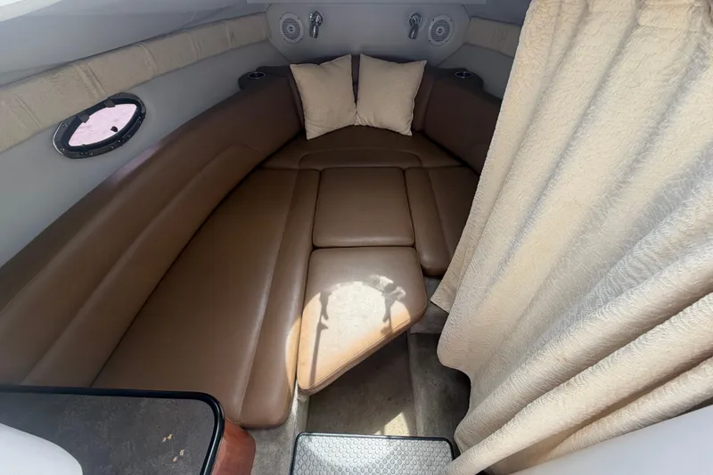 Slide: The Image of 2012 Crownline 236 SC cabin interior with brown seating and beige curtains. - 53