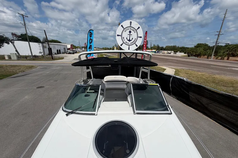Slide: The Image of 2012 Crownline 236 SC boat with black canopy, parked on a sunny day near a road. - 76