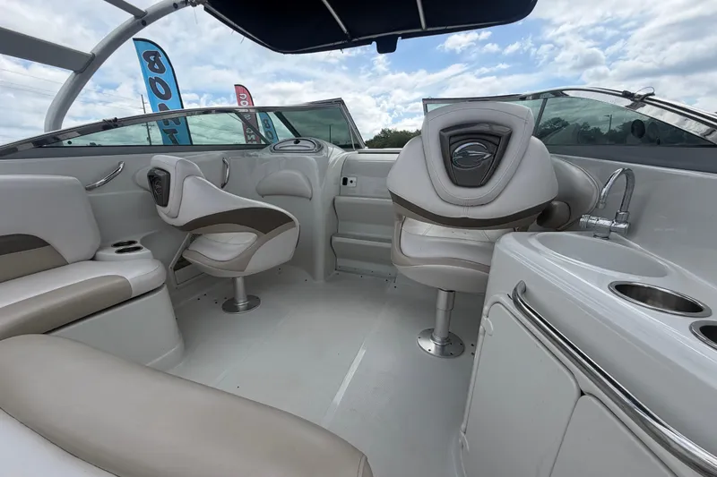 Slide: The Image of 2012 Crownline 236 SC boat interior with seating and sink under a cloudy sky. - 29