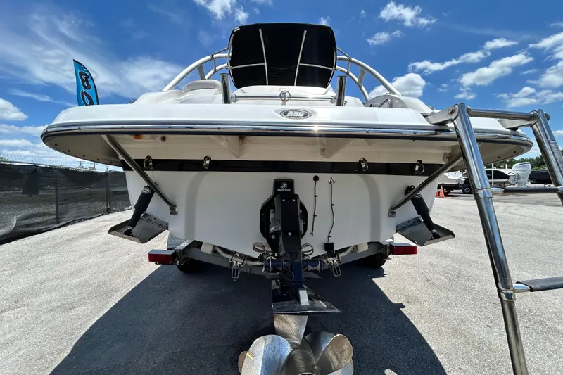 Slide: The Image of 2012 Crownline 236 SC boat rear view with ladder, parked on pavement under blue sky. - 4