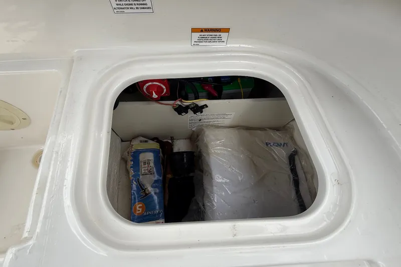 Slide: The Image of Storage compartment of 2024 Bayliner Element M17 boat, featuring safety equipment and battery. - 44