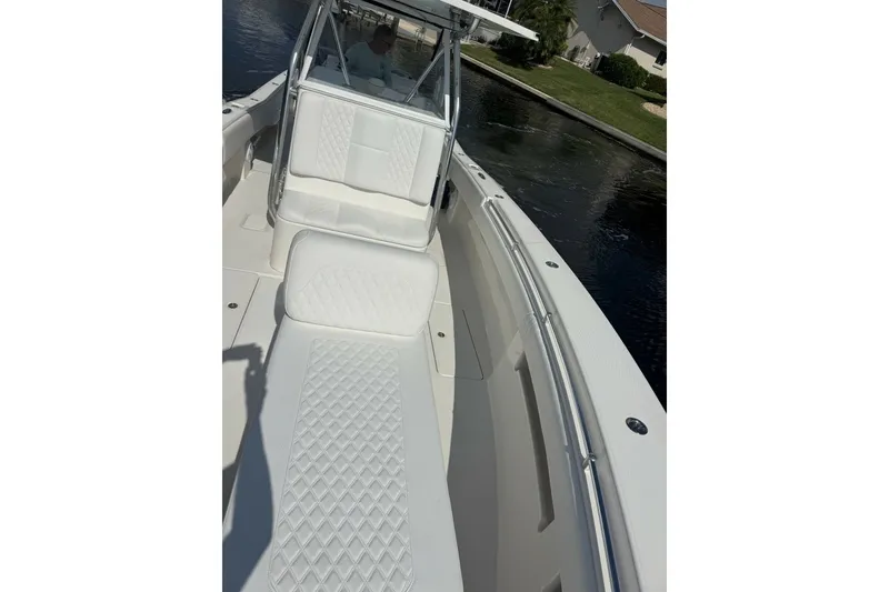 Slide: The Image of 2013 Invincible 36 Open Fisherman boat with white cushioned seating on a calm waterway. - 19